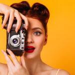portrait of amazed pinup woman with camera charming photographer with red lips taking pictures
